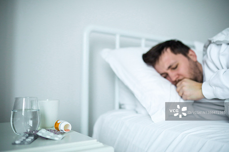 服用药丸且状态不佳的患新型冠状病毒的年轻男人图片素材