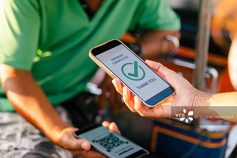 顾客通过智能手机上的二维码以非接触式支付方式支付嘟嘟车车费图片素材