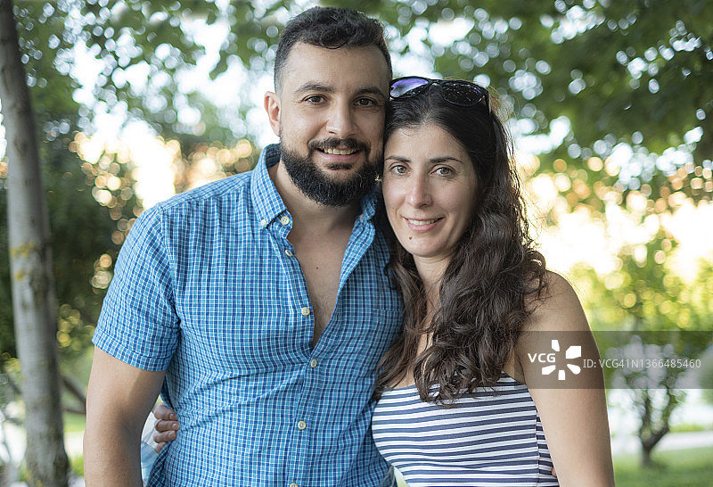 在公园里摆姿势微笑看着镜头的户外情侣图片素材