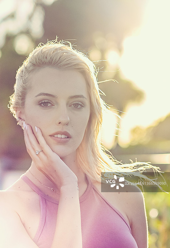 在阳光明媚的夏日头像中，手放在脸上的漂亮女人图片素材