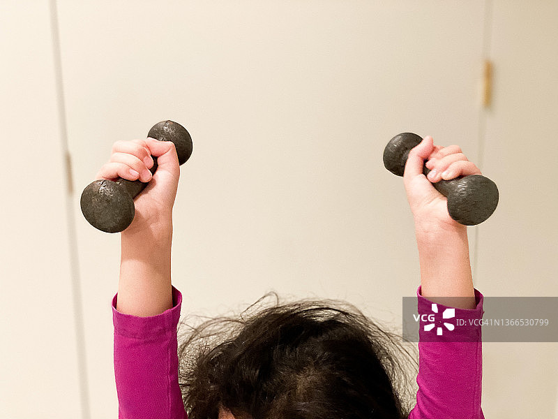 在家中健身房练习举小哑铃的年轻混血女孩图片素材