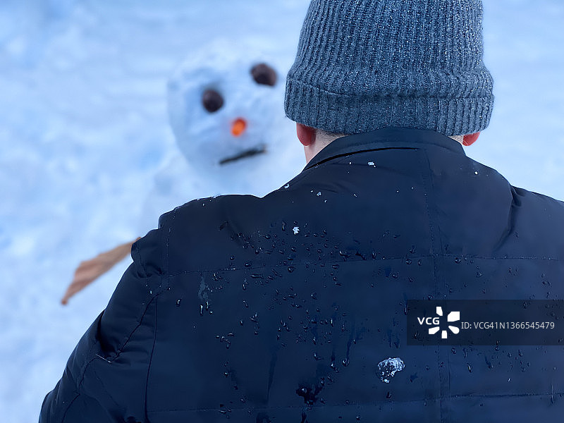 尽管浑身湿透，善良的爸爸还是完成了家庭雪人的收尾工作图片素材