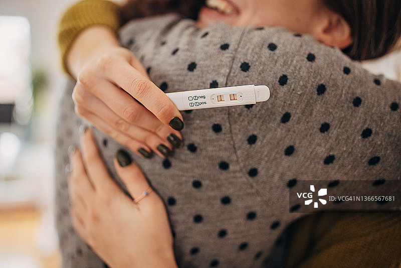 年轻夫妇因怀孕测试呈阳性而拥抱图片素材