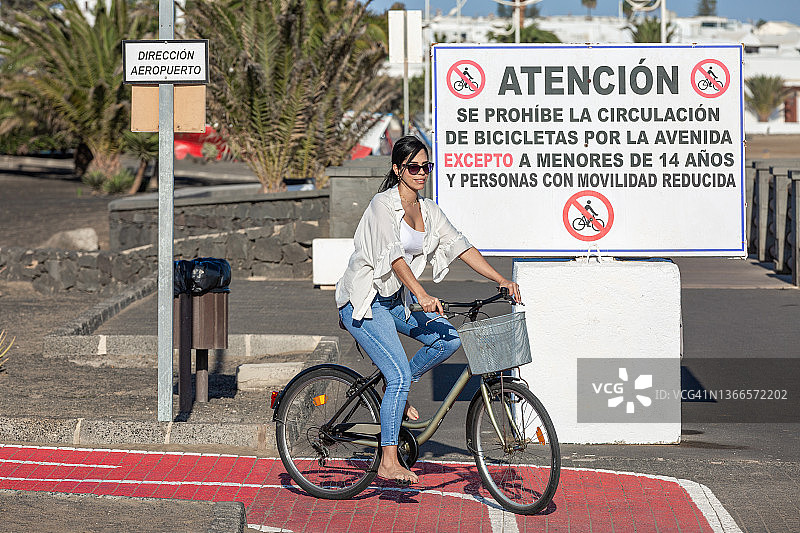 在自行车道上骑自行车的西班牙裔女人图片素材