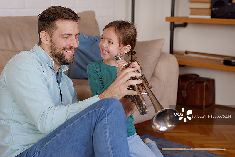 女孩和父亲在家学习吹小号图片素材