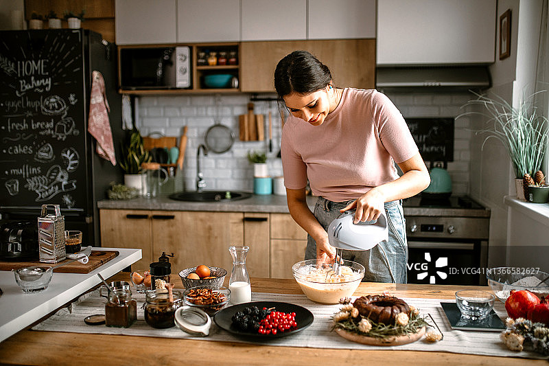 在厨房用电动搅拌器混合蛋糕面糊图片素材