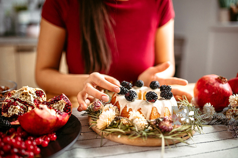 女人在蛋糕上添加新鲜多汁的黑莓图片素材