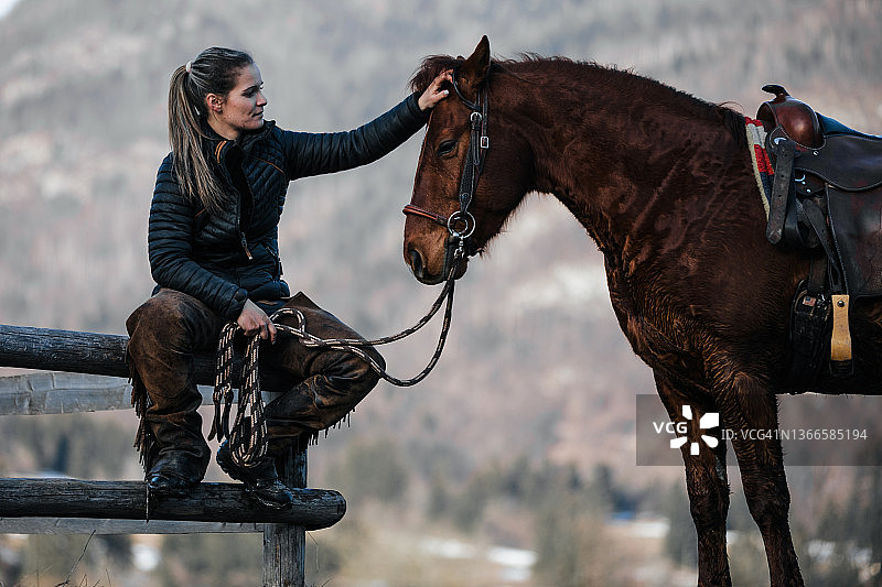 年轻女子抚摸棕色马匹图片素材