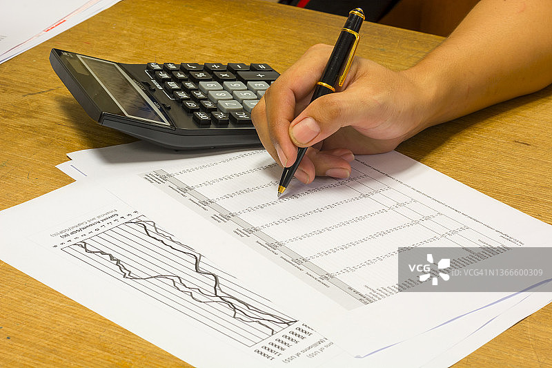 在木桌上使用计算器和会计数据进行金融会计图片素材