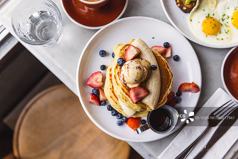咖啡厅早餐：香蕉草莓蓝莓煎饼，高角度拍摄图片素材