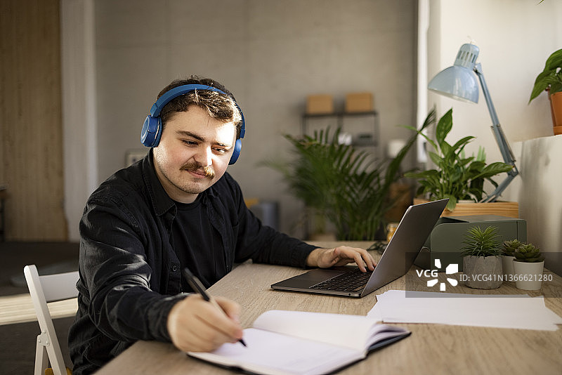 成功的白人男子在家用笔记本电脑工作图片素材