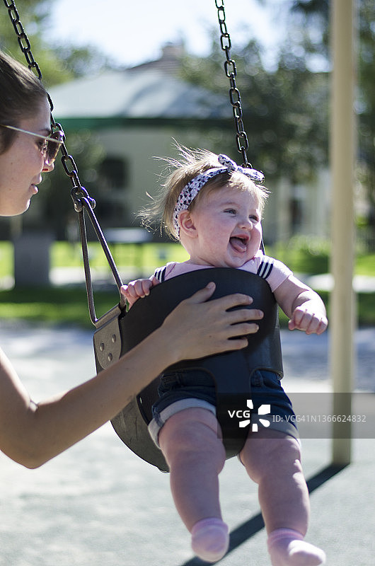 母亲推着秋千上的快乐宝宝图片素材