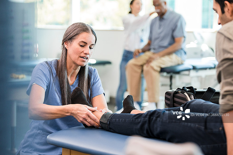 理疗师为男人进行脚踝理疗图片素材