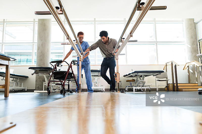 治疗师将助行器移到一边，以便年轻人抓住扶手图片素材