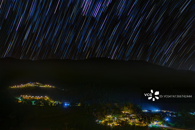 泰国难府乡村夜晚的宁静景色，夜空中星迹环绕图片素材