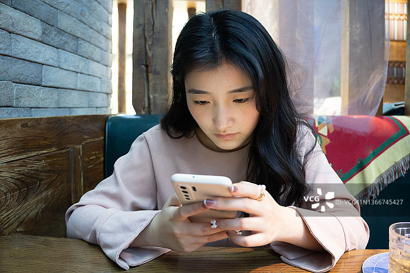 年轻的亚洲女性在餐厅使用手机App在智能手机上下单点餐图片素材