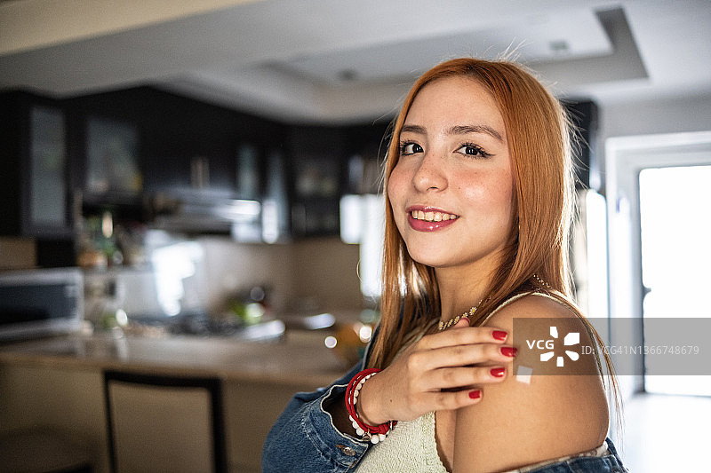 一名接种疫苗后展示手臂的快乐拉丁裔少女图片素材