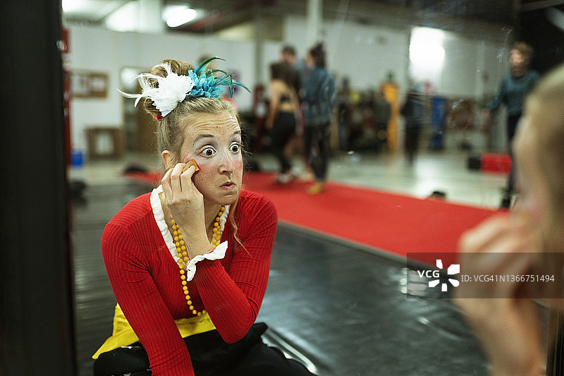 女性小丑马戏团演员在表演和训练前在镜子前化妆图片素材