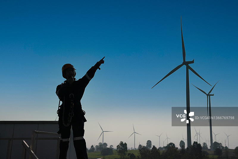 电气工程师身穿全套个人防护装备在风力涡轮机农场工作。图片素材