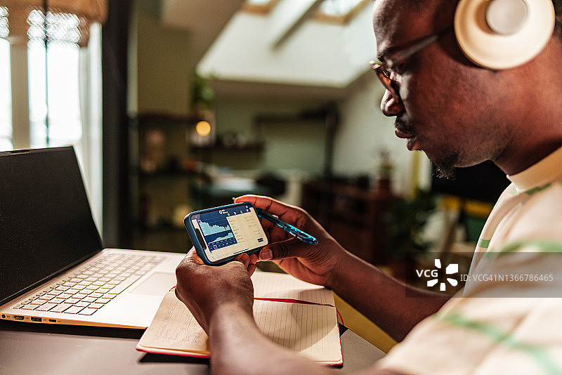 男人在智能手机屏幕上分析加密货币图表图片素材