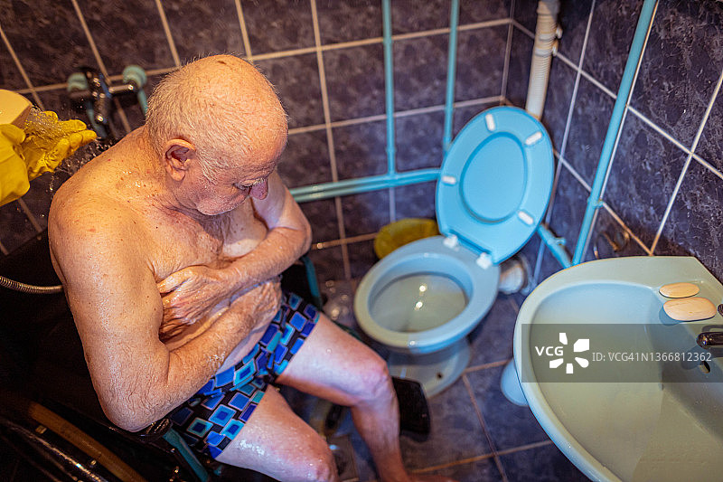 男护士在疗养院为坐轮椅的年长残疾男病人洗澡图片素材