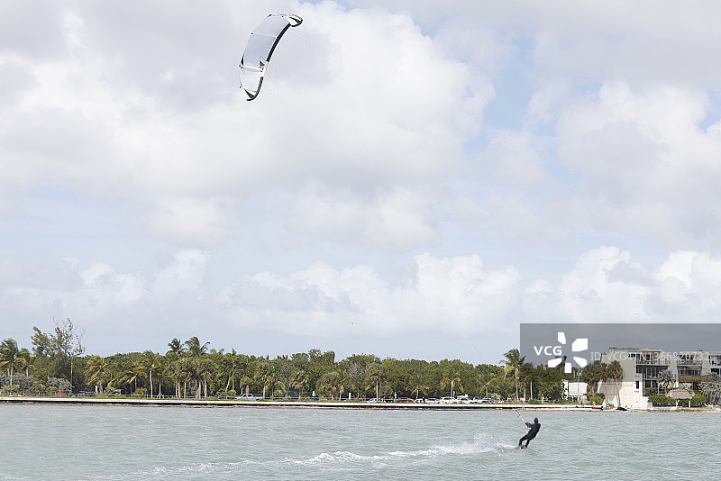 热带城市晴朗的一天，在海中玩滑翔伞的人图片素材