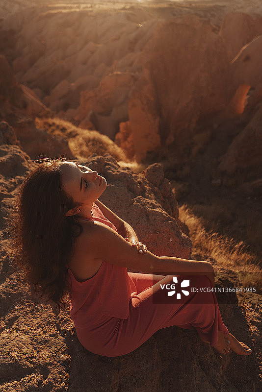 坐在悬崖边看日落的年轻旅行女人图片素材