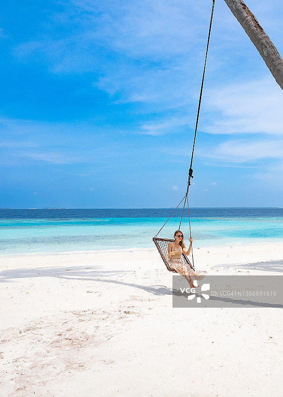 坐在椰子树秋千上的美丽女孩图片素材