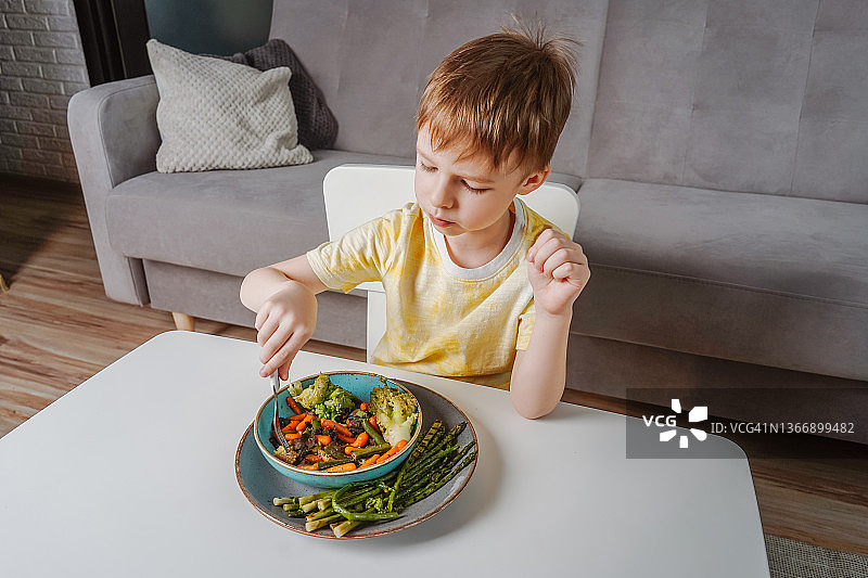 小男孩在客厅里吃蔬菜图片素材