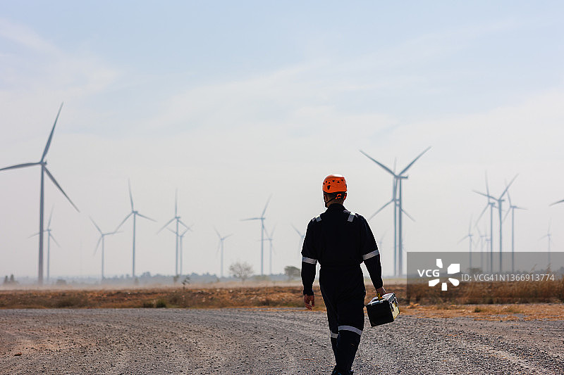 维护工程师携带工具箱在风力涡轮机场中行走图片素材
