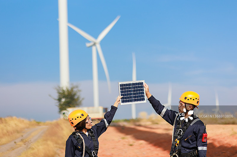 在风力涡轮机领域使用太阳能电池板工作的两名工程师图片素材
