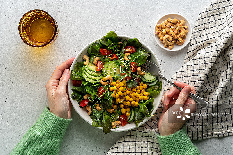 无脸女性食用富含脂肪酸和膳食纤维的纯素沙拉图片素材