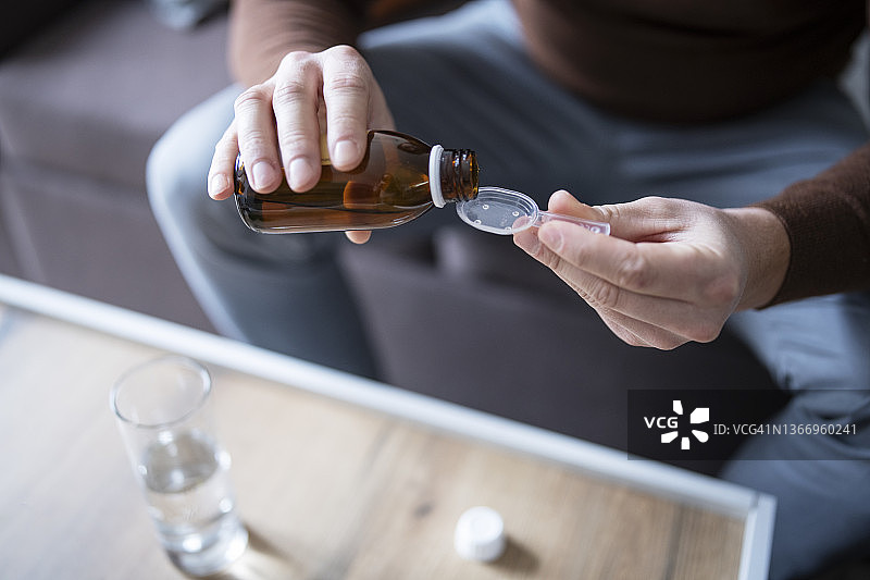 男人倒咳嗽糖浆到勺子里图片素材