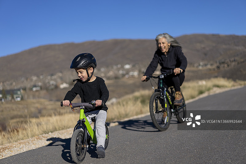 骑自行车追逐孙子的拉丁裔祖母图片素材