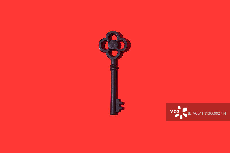 红色背景上的黑色复古钥匙与硬阴影。开锁、门、购买、抵押和租赁概念图片素材