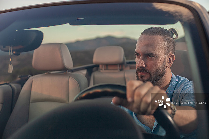 日落时分，男子驾驶敞篷车行驶在风景中图片素材
