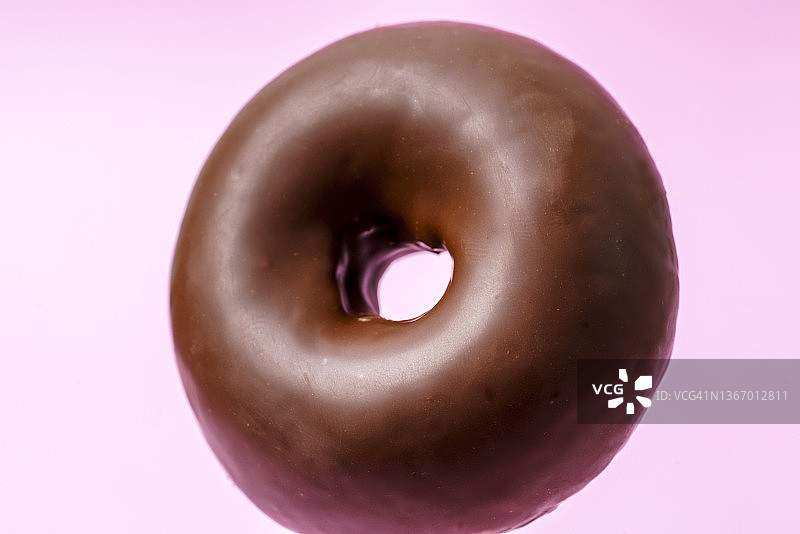 粉色背景上的巧克力甜甜圈图片素材