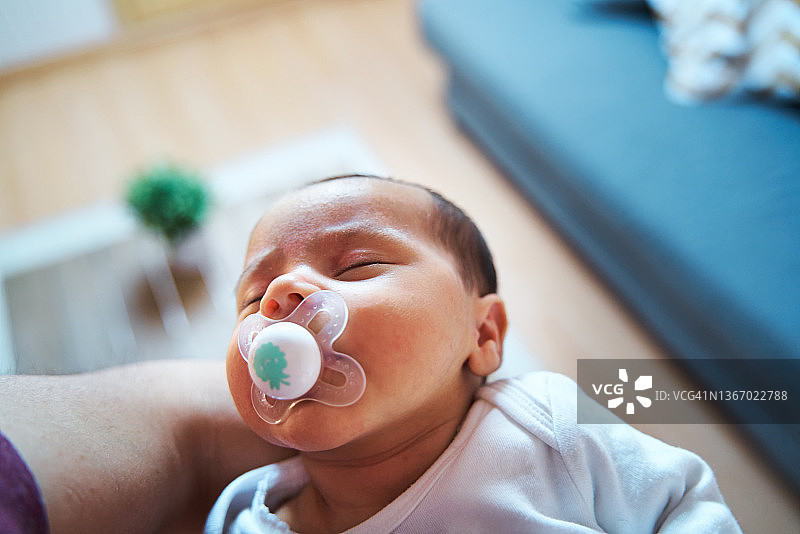 宝宝在大人怀里含着奶嘴睡觉特写图片素材