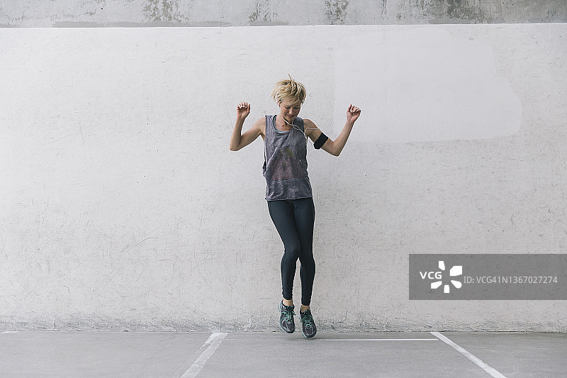 运动时，女子听着音乐跳跃图片素材