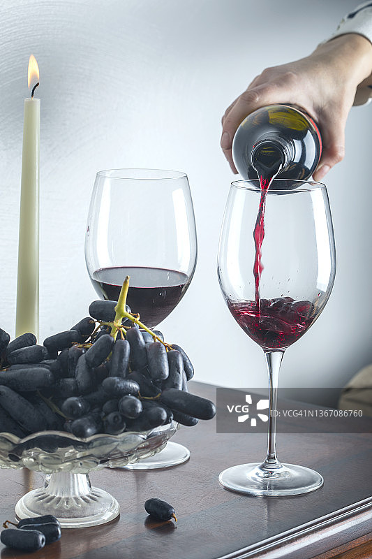 红酒瓶、两个酒杯和桌上的葡萄图片素材