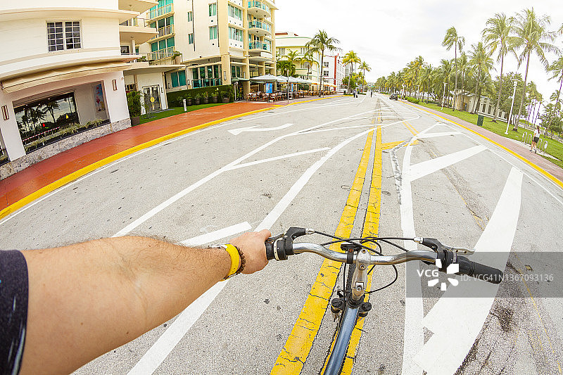 年轻运动男子在迈阿密南海滩海洋大道骑自行车的视角图片素材