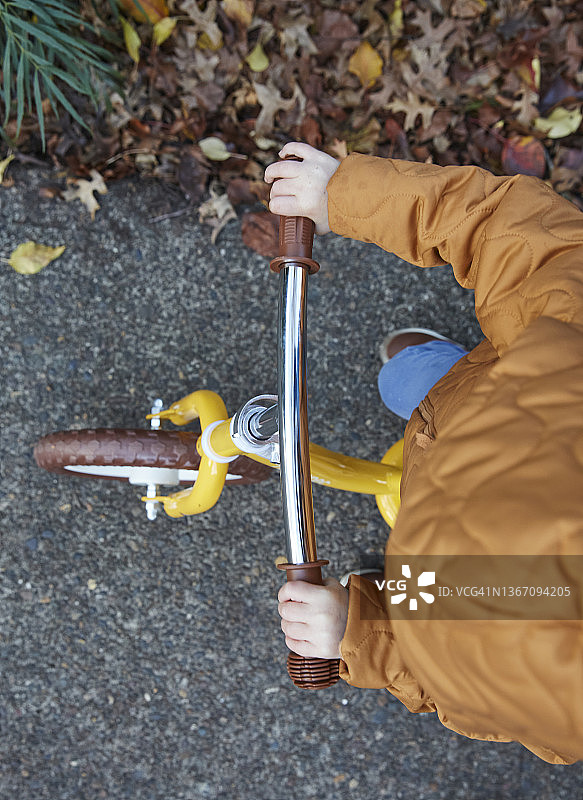 俯视角度拍摄：幼儿在人行道上骑着儿童自行车图片素材