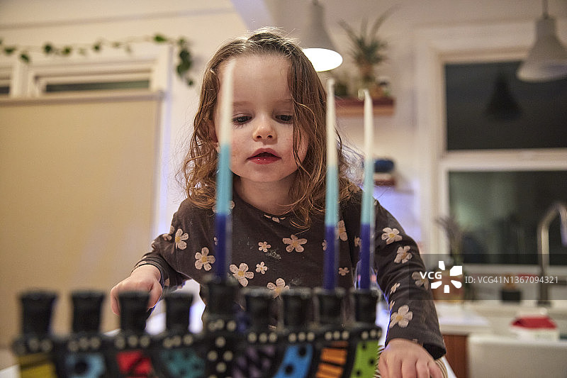 好奇的幼儿在光明节的第二个晚上检查烛台图片素材