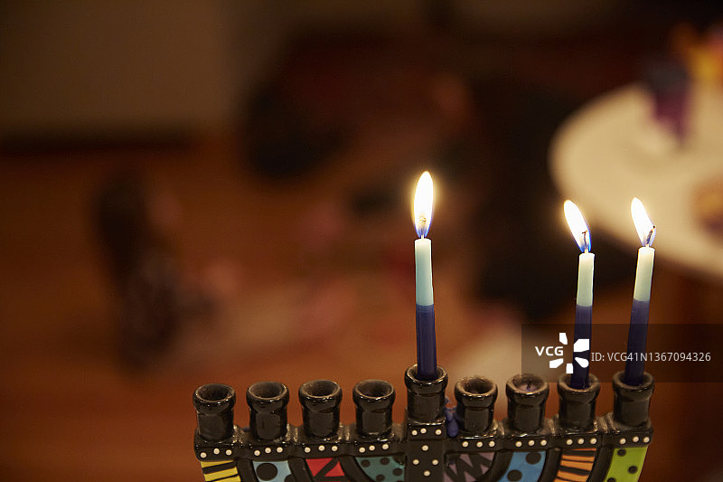 高角度拍摄：光明节蜡烛燃尽，孩子们在背景中玩新礼物图片素材