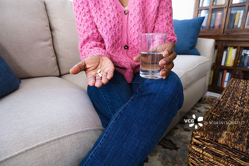 女人拿着胶囊和一杯水图片素材