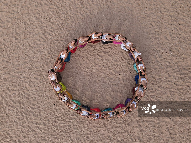 健康的女性在海滩户外一起做瑜伽，团队合作概念图片素材