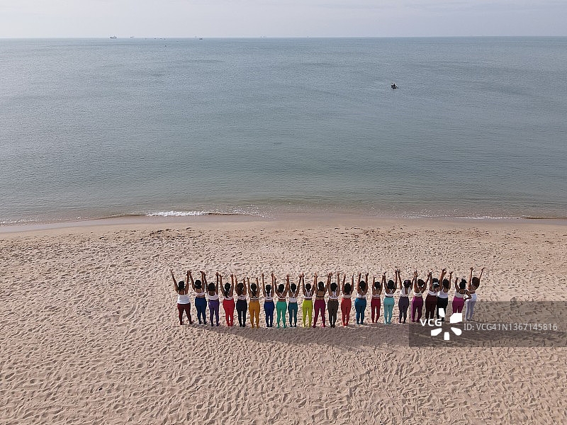 团队合作与商业概念：一群妇女在海滩上练习瑜伽图片素材