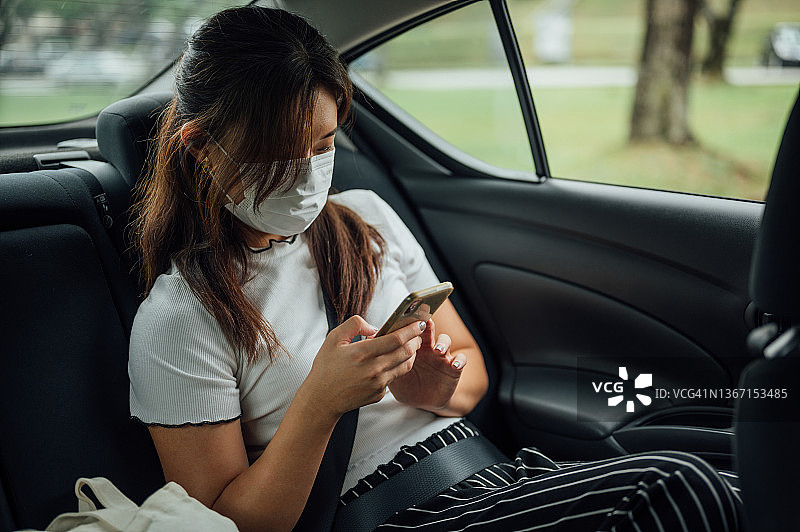 亚洲女商人在车后座使用智能手机通勤图片素材