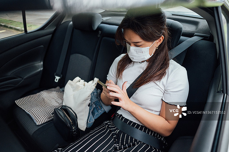 坐在汽车后座上使用智能手机的亚洲女商人图片素材
