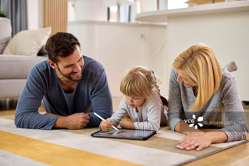 幸福的父母向女儿解释如何使用数位平板电脑。图片素材
